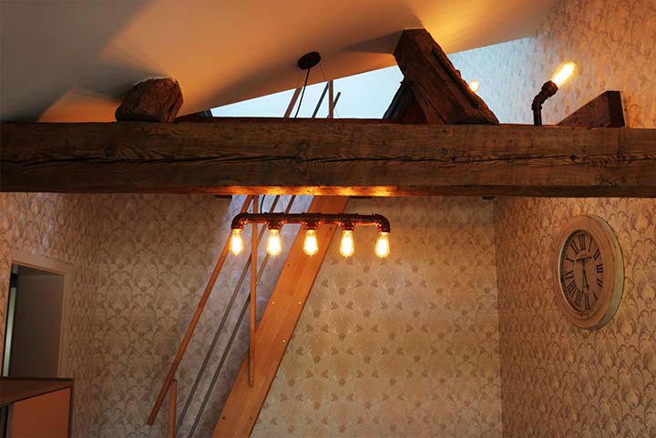 Tapeziertes Wohnzimmer mit Holzbalken und Deckenleuchte